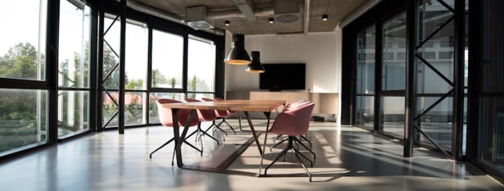 Modern conference room with large windows, a wooden table, and stylish chairs.