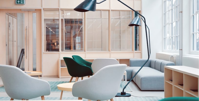 Modern office lounge with stylish chairs, sofa, and large floor lamp.